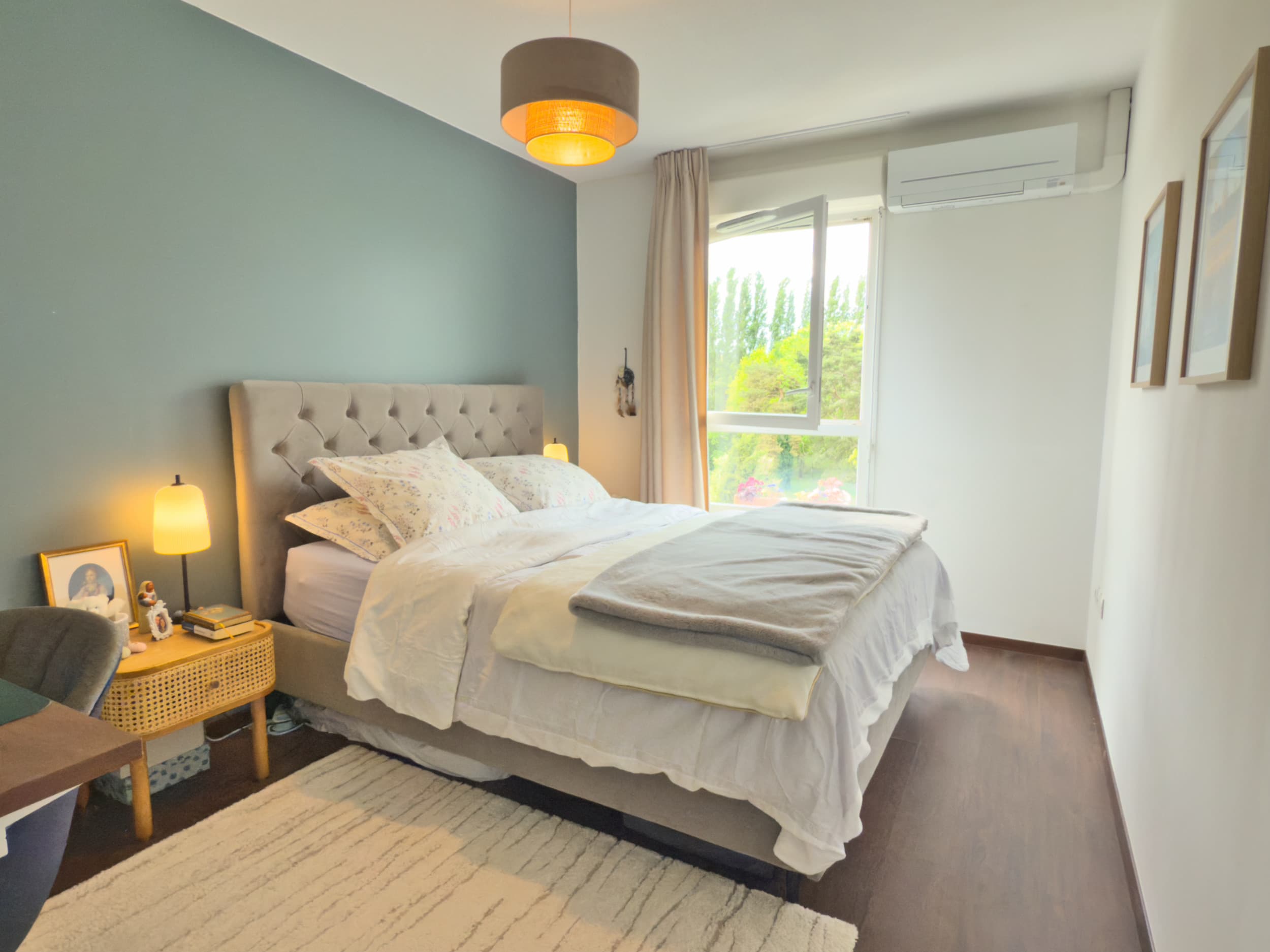 Chambre parentale avec tête de lit capitonnée et vue sur la verdure