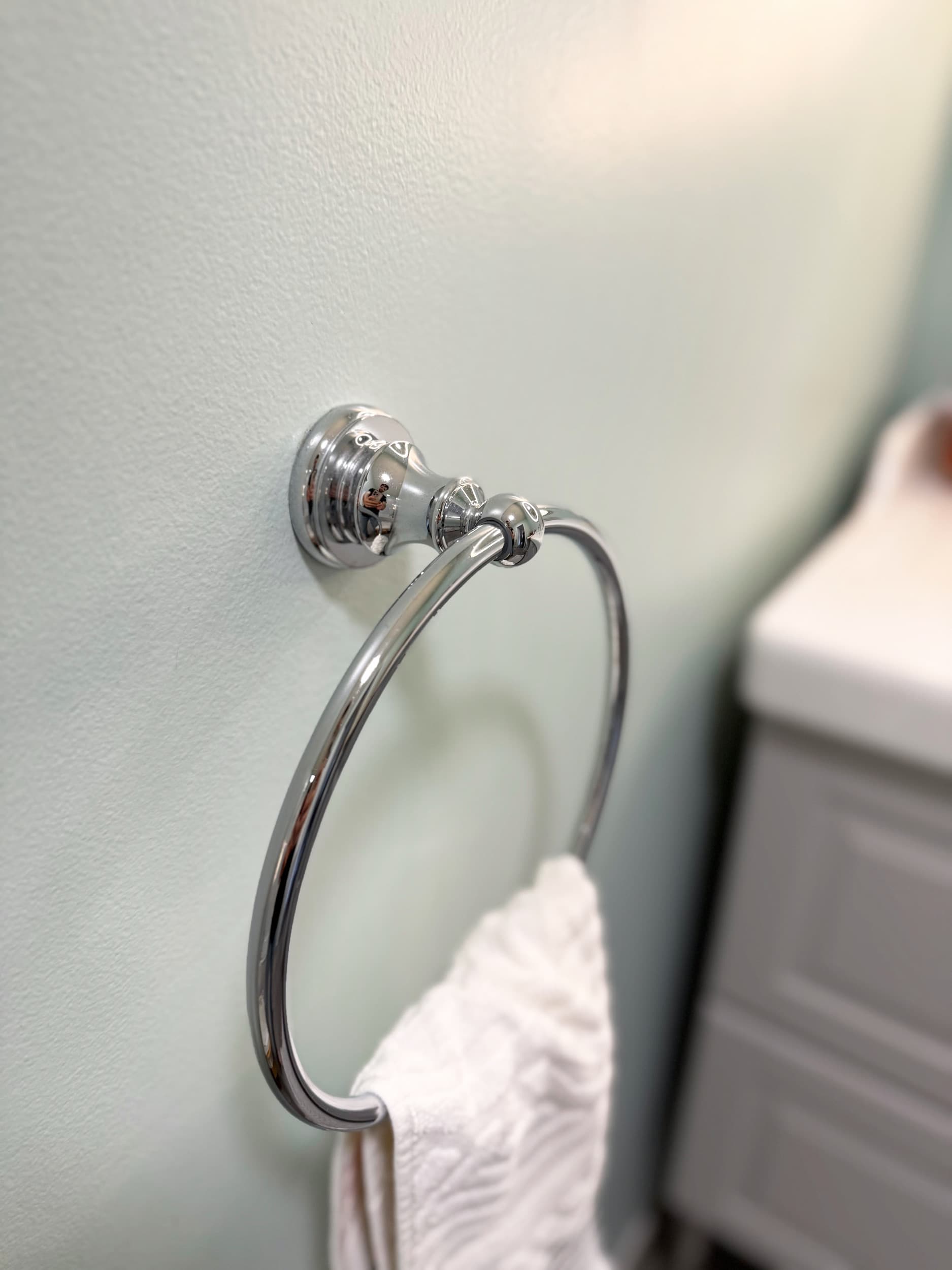 Détail porte-serviette chromé sur mur vert d'eau