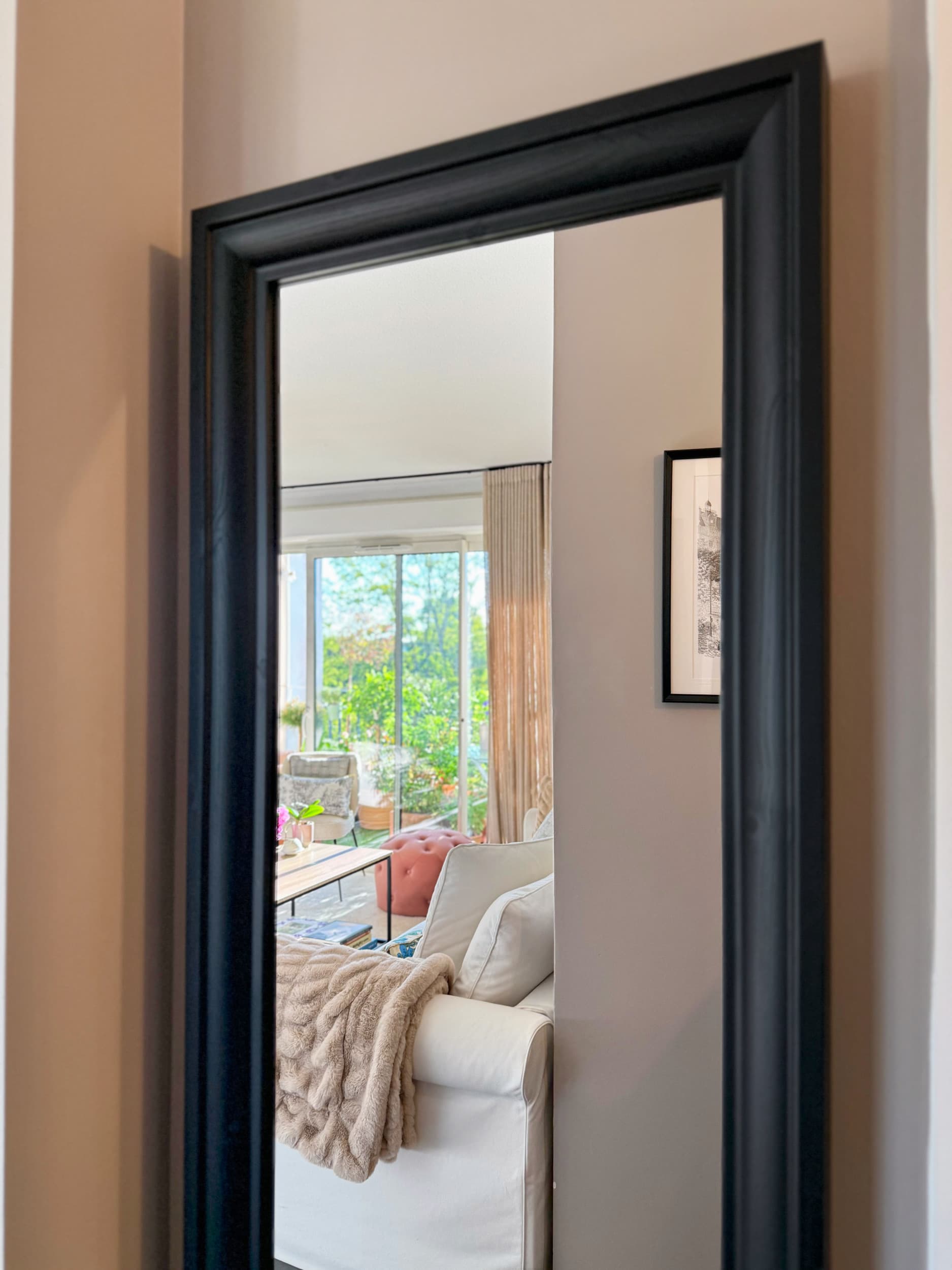 Grand miroir noir reflétant le séjour et le balcon